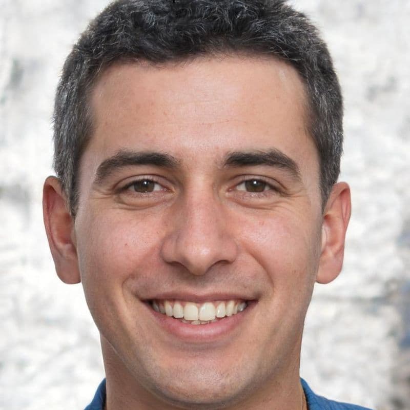 Retrato em close de um homem sorridente com cabelo curto escuro e olhos castanhos.